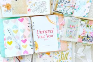 Susannah Conway's Unravel Your Year workbook on top of a pile of unraveling journals
